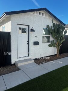 White house with door and cactus along wall. 